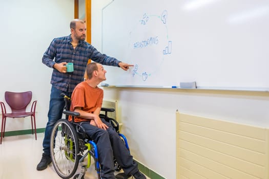 Man with disability and work team during brainstorming in a meeting room using a white board