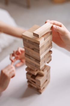 two women playing a board game made of wooden blocks at home, excitement and relaxation, mind development concept, hand motor skills,