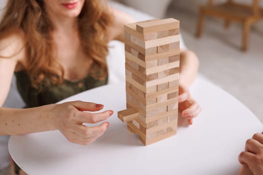 two women playing a board game made of wooden blocks at home, excitement and relaxation, mind development concept, hand motor skills,