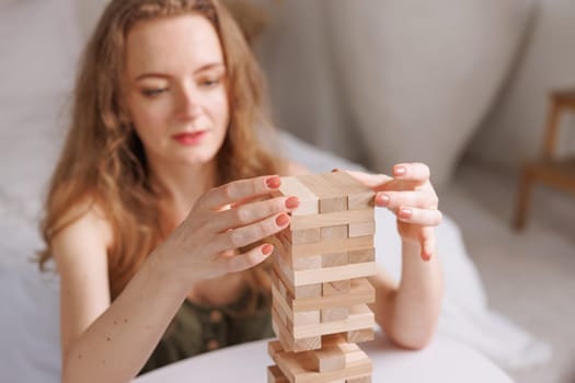 two women playing a board game made of wooden blocks at home, excitement and relaxation, mind development concept, hand motor skills,