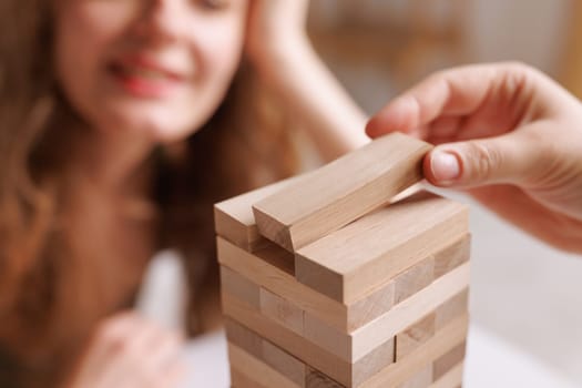 two women playing a board game made of wooden blocks at home, excitement and relaxation, mind development concept, hand motor skills,