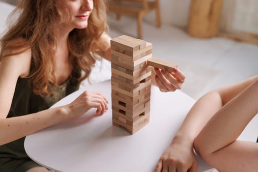 two women playing a board game made of wooden blocks at home, excitement and relaxation, mind development concept, hand motor skills,