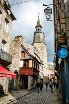 dinan,france,28-04-2024:shopping street with the Clock tower in the medieval town of Dinan, France.