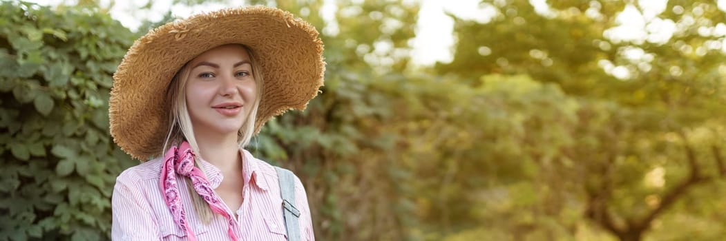 Beautiful young woman gardening outside in summer nature.