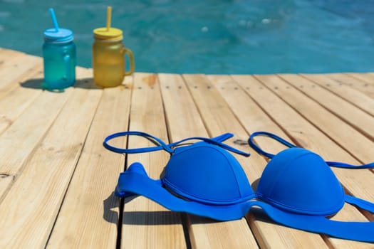 Swimsuit and two cocktails of yellow and blue standing by the pool. Pool party outdoors.