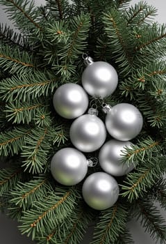 A close-up image showcasing a cluster of silver Christmas ornaments nestled amongst vibrant green evergreen branches. The ornaments reflect light, creating a sparkling effect, while the lush branches create a backdrop of natural beauty.