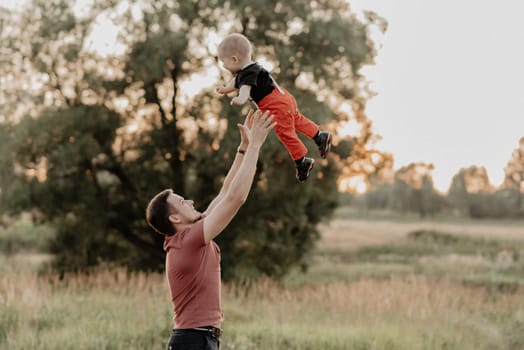 dad throws his little son in the field in the summer. Added grain simulates film photo