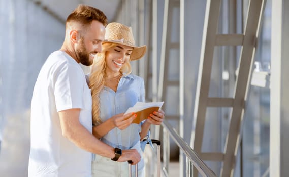 Ready For A Trip Concept. Smiling spouses holding their passports and tickets standing at airport window