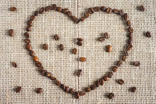 Coffee beans laying down in a heart shape, On a Burlap fabric. Background voor coffee related products.