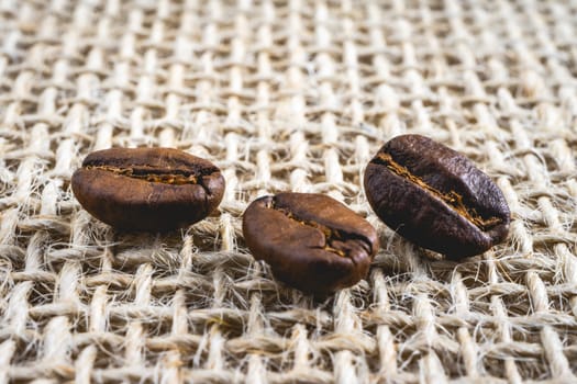 Close up from a few coffee beans laying down on a Burlap fabric background. Background voor coffee related products.