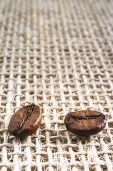 Close up from a few coffee beans laying down on a Burlap fabric background. Background voor coffee related products.
