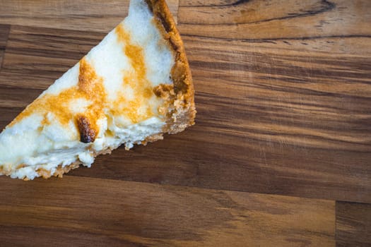 A slice of a fresh home made lemon pie, on a wooden background.