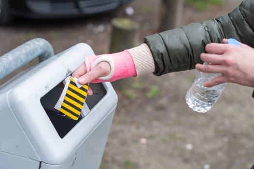 woman with a pink cast on her arm throws garbage into a street trash can, ecology of a modern city, limited mobility