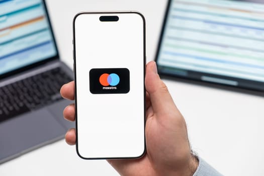 PRAGUE, CZECH REPUBLIC - JANUARY 21 2024: Mastercard logo on the screen of smartphone in mans hand on the workplace background.