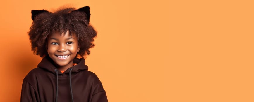 Banner of Cute african american girl in cat halloween costume looking at camera and smiling over orange background. Happy Halloween. Trick or treat