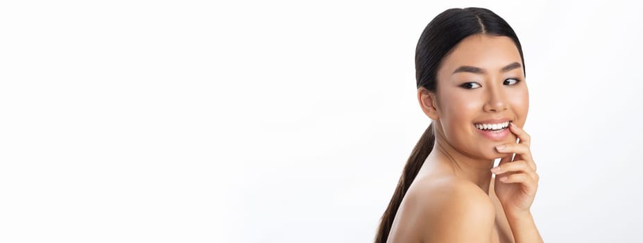 Portrait of attractive naked young asian lady posing on white studio background, cheerfully smiling at camera, copy space. Skin and body care for young women, healthy lifestyle concept