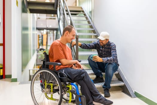 Man with disability talking with colleague in a coworking coffee break into a modern building