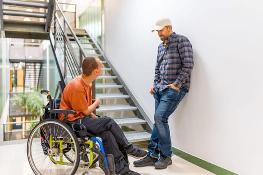Man with disability talking with a colleague in a modern coworking during a work break