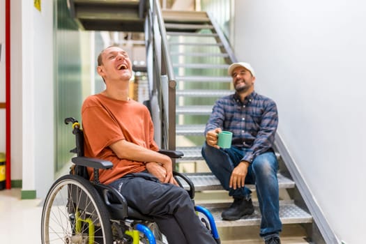 Male caucasian freelance and disabled coworker laughing and talking during coffee break at coworking