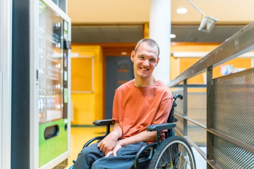 Caucasian smiling man with cerebral palsy next to a vending machine in a modern coworking