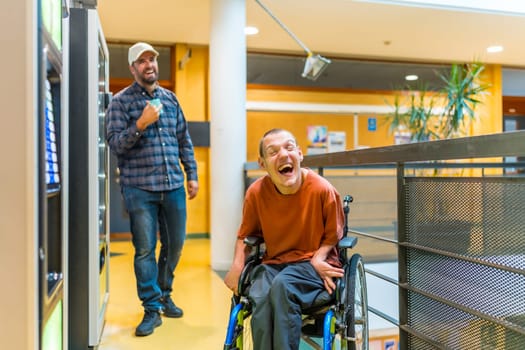 Man with cerebral palsy laughing next to coworker during a work break walking into vending machines