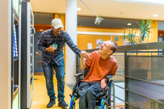 Disabled man and coworker having fun during work break joking next to vending machine in a modern coworking
