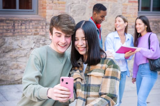 Happy multiracial students using cell phone to chat online. University life concept