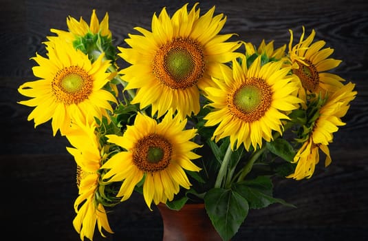Beautiful yellow bouquet of sunflowers in a clay jug.
