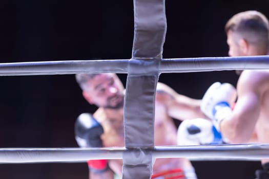 A man is boxing and the referee is watching. The man is wearing a white glove. The referee is looking at the man's face