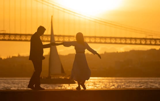 A couple dancing on a pier by the water. The sun is setting in the background. Scene is romantic and peaceful