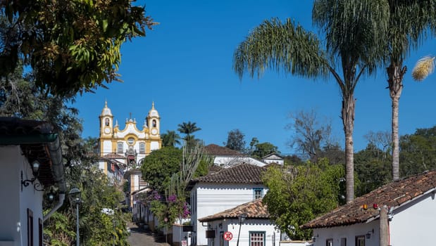 A beautiful colonial town in Brazil with a baroque church, lush trees, and traditional houses.