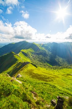 Vertical view of volcanic landscape and Puy Mary in summer. Backlit photograph taken in France