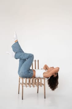 Happy beautiful girl posing in a new hot summer look. Wearing blue jeans and white waistcoat.