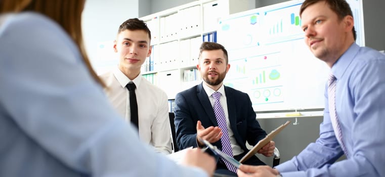 Young handsome teacher man in suit with workgroup seminar board with chart coaching background. Lecturer for applicants retraining financial statistics management enterprise etiquette corporate spirit