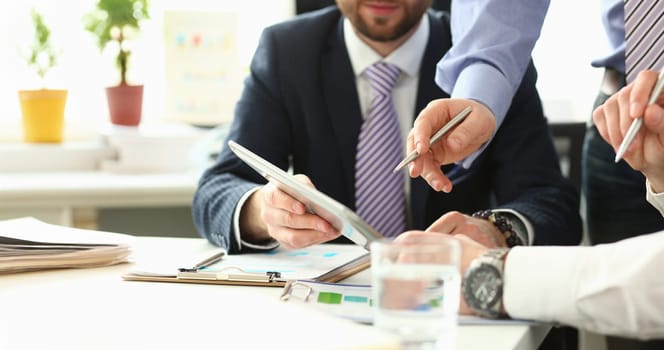 Group businessman are looking and studying statistics on tablet display closeup. Male hand opponent holds pen and points out problem collaboration business coach cooperation partnership palm concept