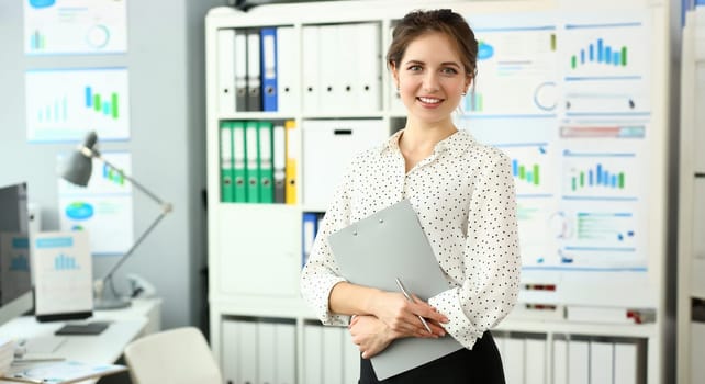 Adult caucasian fashion attractive businesswoman smile workplace background look at camera. Hold one clipboard and pen in hand white collar worker model casual modern dress concept