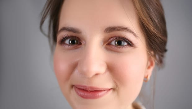 Beautiful european woman portrait. Worth a gray background and smiling beauty fashion style curly hair with white strands view of the eye in the camera