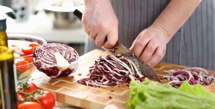 Chef Hands Slicing Purple Salad Cabbage Halve. Male Chopping Red Cole on Cutting Board in Kitchen at Home. Healthy Grocery Culinary Recipe. Fresh Dieting Ingredient Horizontal Photography