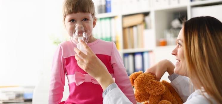 Little girl breathing with inhaler at doctor office portrait