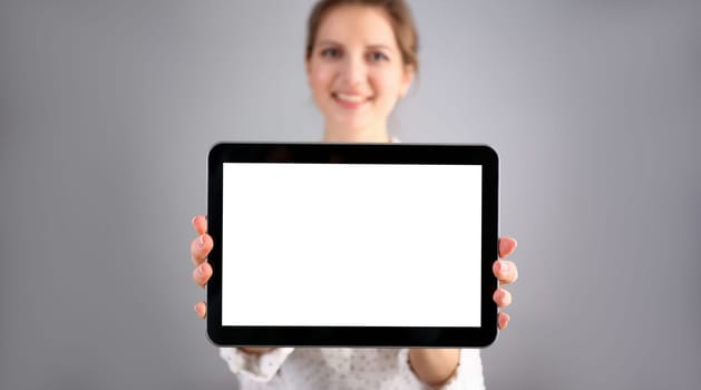 Female hand holds black frame tablet pad on gray background setting while sitting on couch engaged an internet surfing using application mail tracking food delivery display leisure concept closeup.
