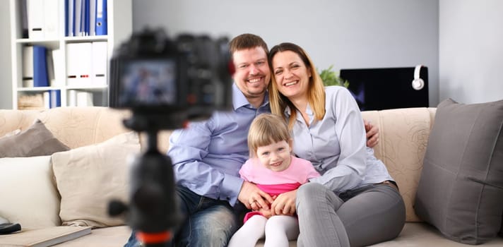 Young happy family sit on couch making photo session portrait looking at camera