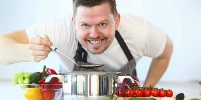 Satisfied Culinary Chef Holding Kitchen Spoon. Kitchen Vlog for Vegetarian. Cook with Soup Ladle in Hand. Organic Vegetables. Man Cooking from Red Tomato and Cabbage Looking at Camera Shot.