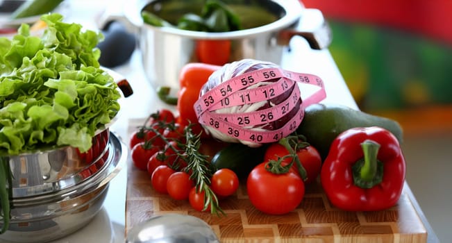 Healthy Fresh Vegetables Assortment Measuring. Organic Red Cherry Tomato, Ripe Pepper, and Cabbage Wrapped in Centimeter on Kitchen Worktop. Green Lettuce in Saucepan. Horizontal Photography