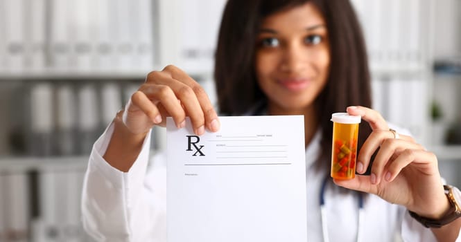 Female black doctor hands hold and give to visitor prescription and jar of pills closeup. Panacea life save healthy lifestyle prescribe treatment legal drug store contraception concept