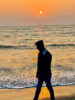 A solitary man walking along a sandy beach, enjoying the calming waves and the open sky. Perfect for lifestyle, travel, and leisure projects.