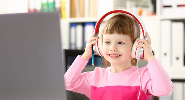 Little girl wearing headphones use mobile computer portrait