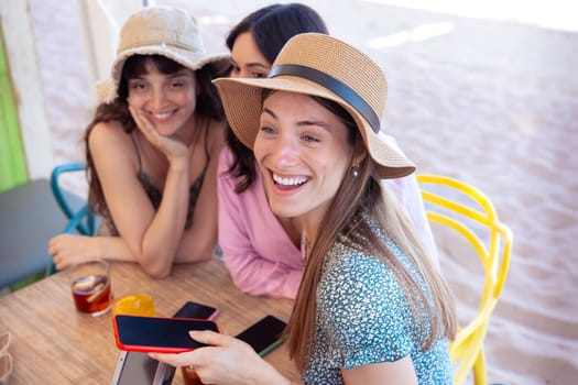 Three happy friends who are in the restaurant with drinks, pay with contactless payment via mobile phone app