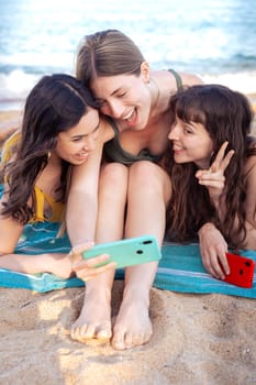 Group of smiling multiethnic women enjoying vacation. Beautiful and cheerful Gen Z girls with their mobile phones pose looking at the camera with a mobile phone.
