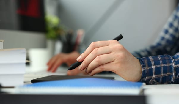 A young designer holds pen from tablet in hand working on new project for customer in field of building construction projects.