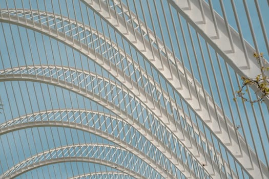 Detailed view of modern lattice arches with geometric patterns against a blue sky. The design highlights innovative architectural elements and structural elegance.